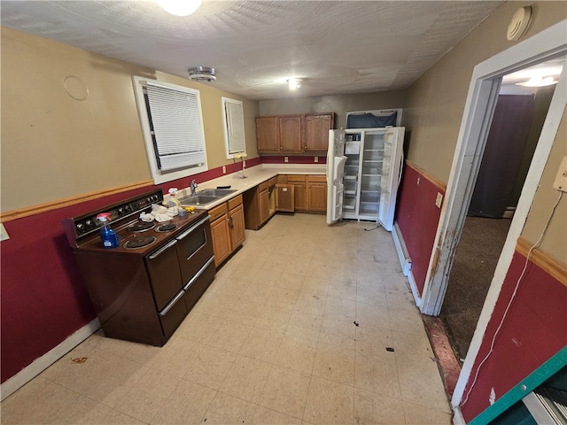 kitchen with a textured ceiling, black / electric stove, and sink