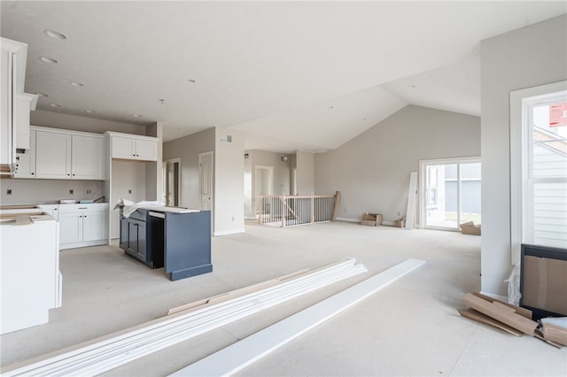 kitchen with vaulted ceiling, white cabinets, and a kitchen island