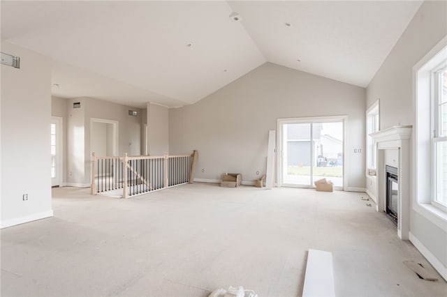 unfurnished living room featuring light carpet, vaulted ceiling, and a wealth of natural light