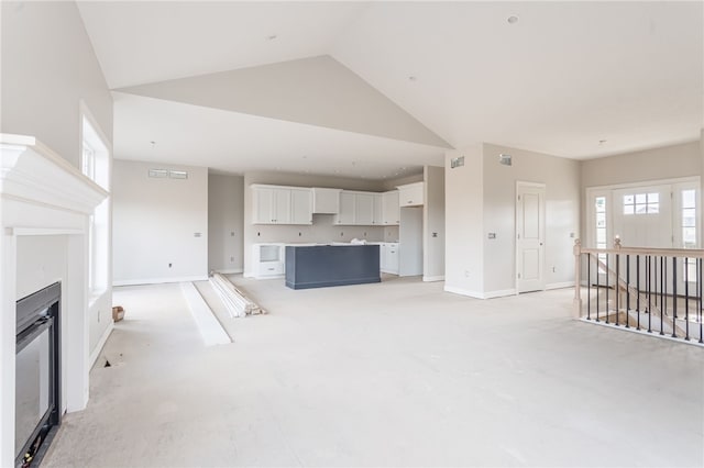 unfurnished living room featuring high vaulted ceiling