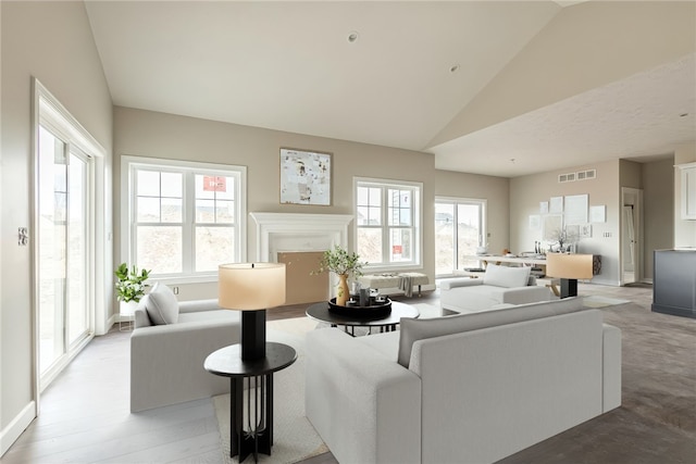 living room featuring light wood-style floors, visible vents, plenty of natural light, and high vaulted ceiling