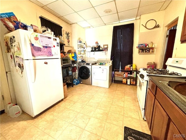 kitchen featuring white appliances, washing machine and dryer, a paneled ceiling, dark countertops, and brown cabinets