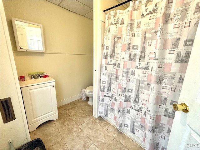 bathroom featuring a sink, toilet, tile patterned floors, a shower with shower curtain, and a paneled ceiling