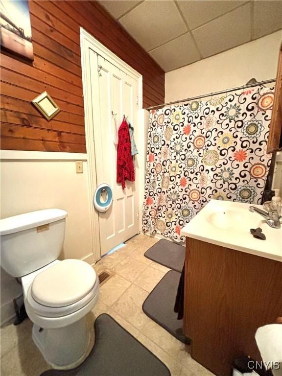 bathroom featuring toilet, a paneled ceiling, vanity, wood walls, and curtained shower