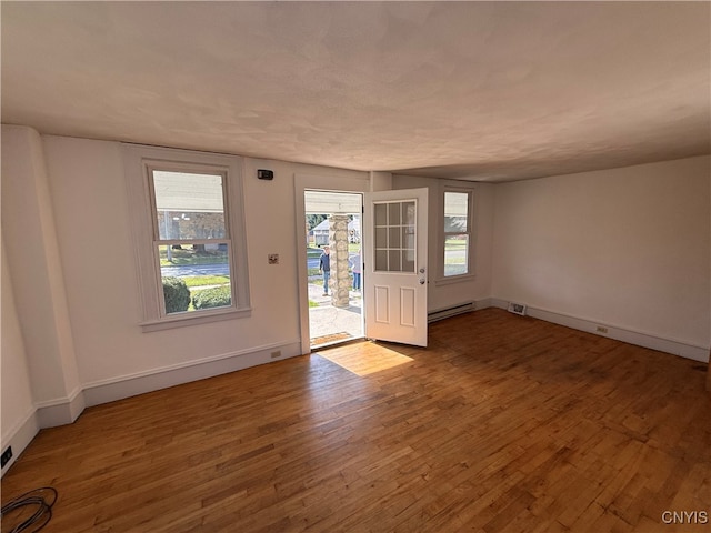 spare room featuring wood-type flooring and baseboard heating