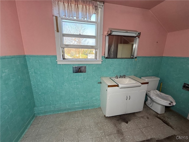 bathroom with vanity, tile walls, vaulted ceiling, and toilet