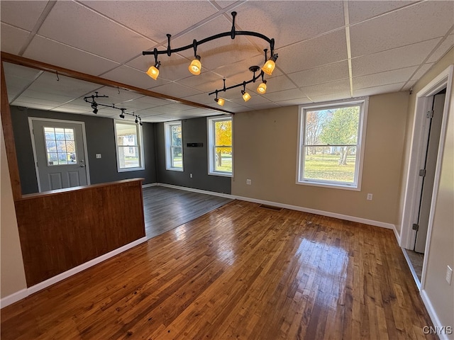 empty room featuring wood-type flooring and a paneled ceiling