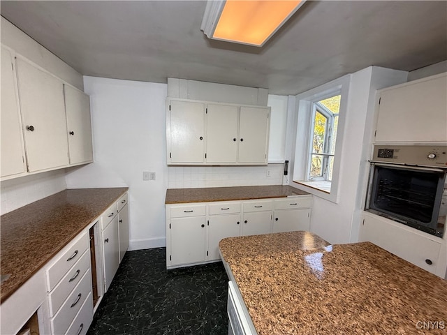 kitchen featuring white cabinetry, backsplash, and oven