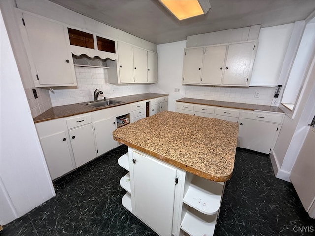 kitchen with white cabinetry, decorative backsplash, a center island, and sink