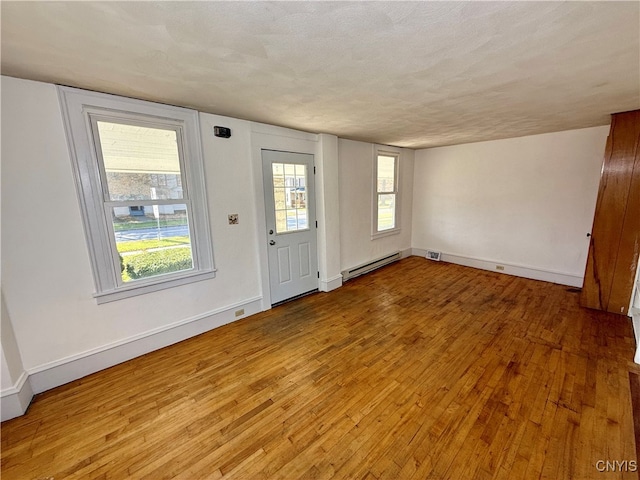 entrance foyer with light hardwood / wood-style flooring, a baseboard heating unit, and a textured ceiling