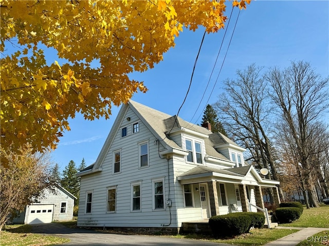 view of side of property with covered porch, an outbuilding, and a garage