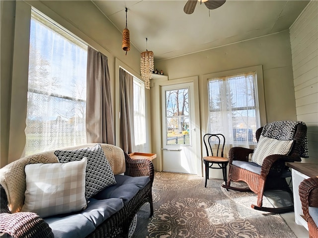 sitting room featuring ceiling fan, carpet floors, and wood walls