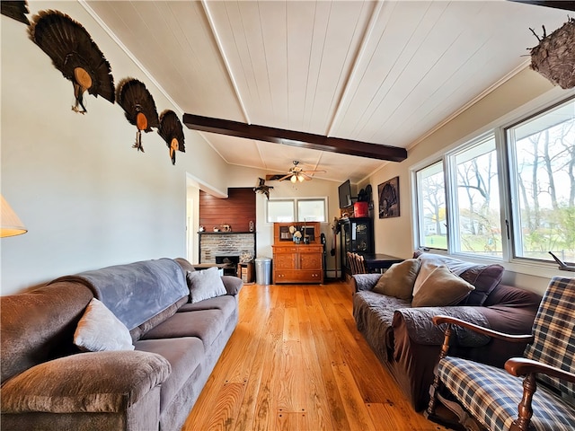 living room with ceiling fan, light wood-type flooring, vaulted ceiling with beams, ornamental molding, and a fireplace