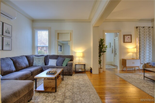 living room featuring hardwood / wood-style flooring, ornamental molding, and a wall unit AC