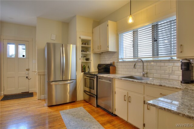 kitchen featuring light hardwood / wood-style flooring, stainless steel appliances, sink, decorative light fixtures, and white cabinetry