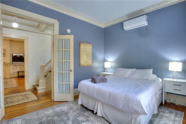 bedroom featuring crown molding, a wall unit AC, and hardwood / wood-style flooring