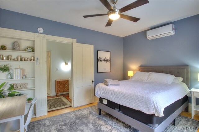 bedroom with ceiling fan, wood-type flooring, and a wall unit AC