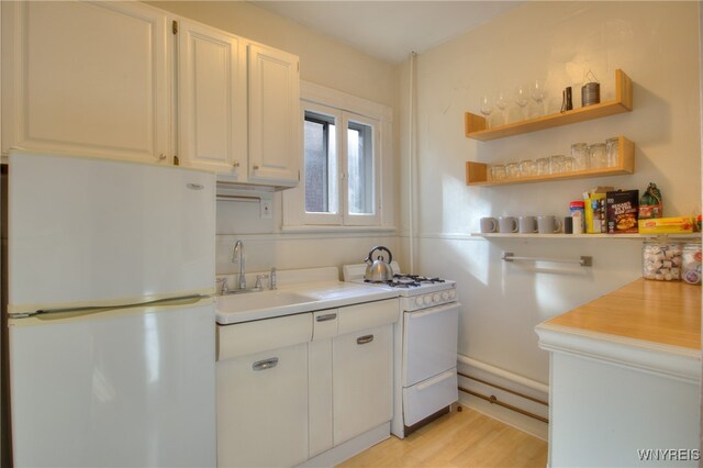 kitchen featuring white cabinets, sink, light wood-type flooring, and white appliances