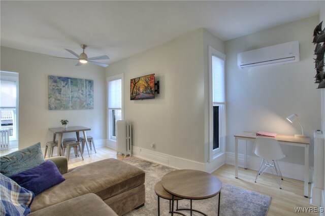 living room with an AC wall unit, light hardwood / wood-style flooring, radiator heating unit, and plenty of natural light