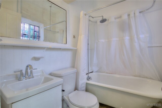 full bathroom featuring vanity, shower / tub combo with curtain, toilet, and tile walls