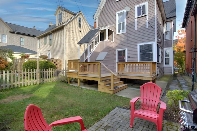 rear view of property featuring a patio, a wooden deck, and a yard