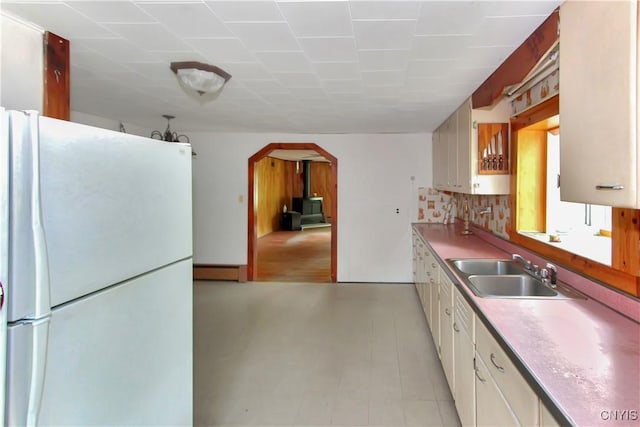 6736 Pine Grove Rd, Watson, NY 13343 - kitchen with freestanding refrigerator, arched walkways, white cabinets, light countertops, and backsplash
