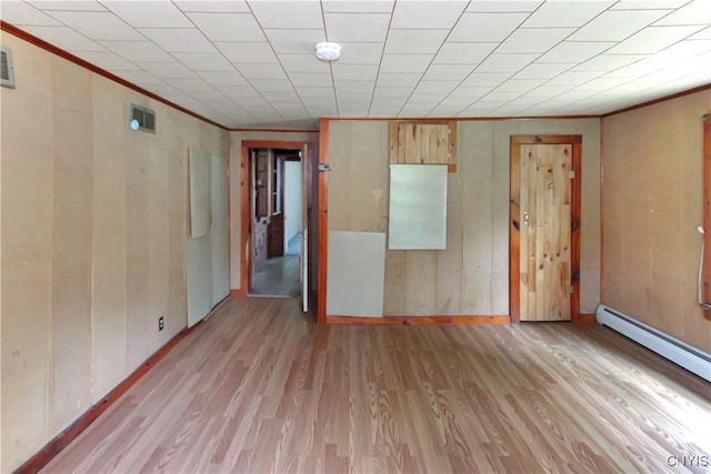 6736 Pine Grove Rd, Watson, NY 13343 - unfurnished room featuring baseboard heating, light wood-style flooring, crown molding, a smoke detector, and wooden walls