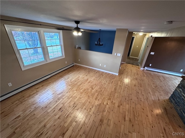 empty room featuring light hardwood / wood-style flooring, baseboard heating, and ceiling fan with notable chandelier