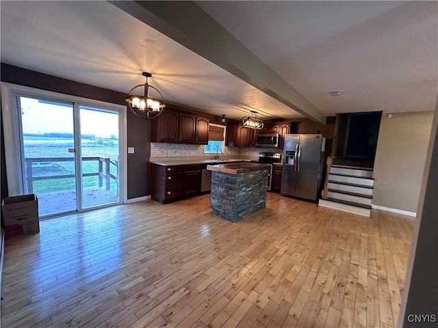 kitchen featuring a center island, appliances with stainless steel finishes, light hardwood / wood-style flooring, and backsplash