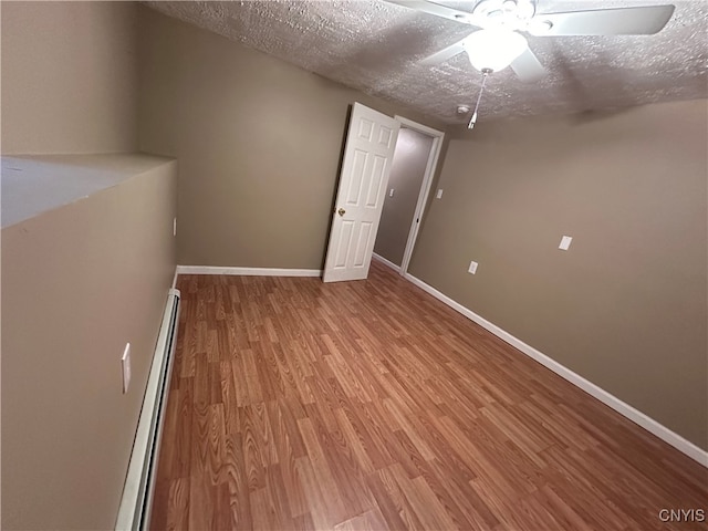 spare room with a textured ceiling, baseboard heating, wood-type flooring, and ceiling fan