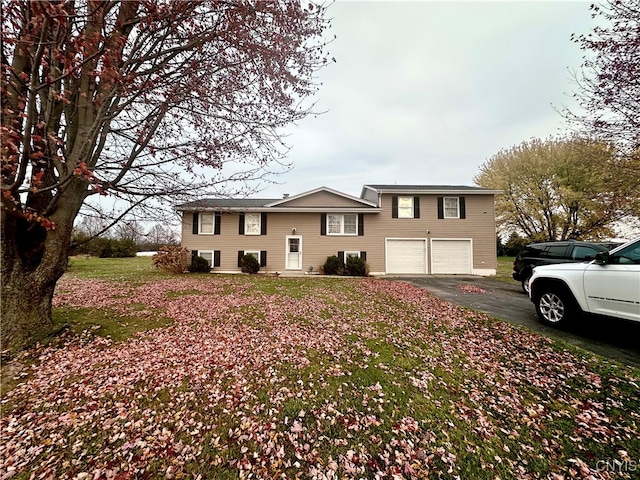 raised ranch with a front lawn and a garage