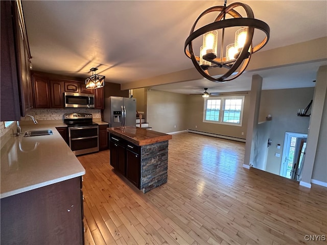 kitchen with a baseboard heating unit, dark brown cabinets, stainless steel appliances, a center island, and light wood-type flooring