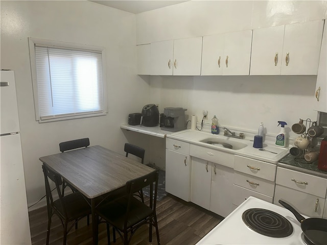 kitchen with stove, dark hardwood / wood-style flooring, sink, white refrigerator, and white cabinets