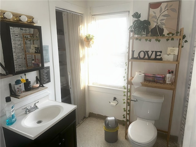 bathroom with tile patterned floors, vanity, a healthy amount of sunlight, and toilet