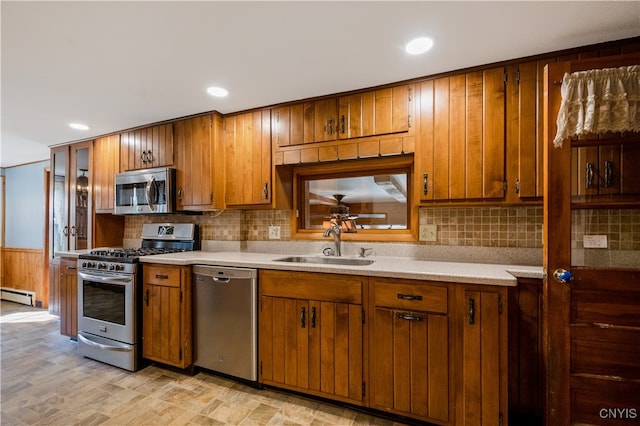 kitchen featuring decorative backsplash, baseboard heating, stainless steel appliances, and sink