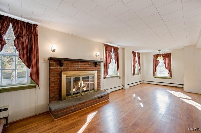 unfurnished living room with a baseboard radiator, light hardwood / wood-style flooring, plenty of natural light, and a brick fireplace