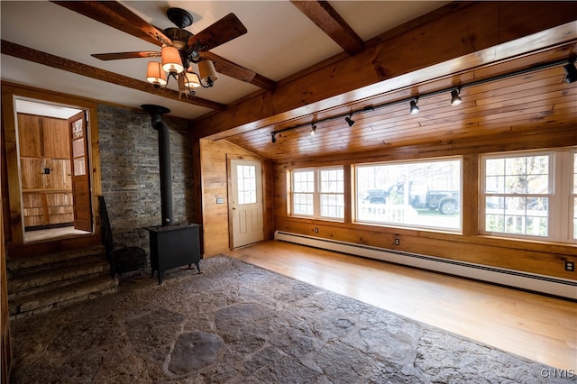 interior space with track lighting, baseboard heating, a wood stove, hardwood / wood-style floors, and ceiling fan