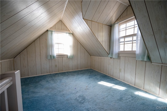 additional living space with a healthy amount of sunlight, lofted ceiling, carpet floors, and wooden walls