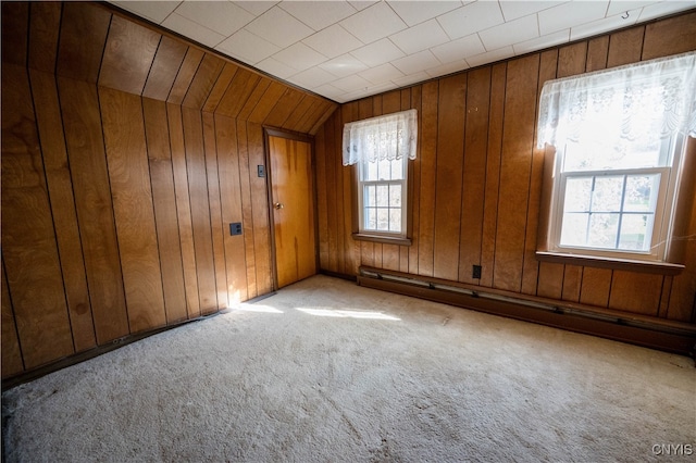 spare room with lofted ceiling, wooden walls, light carpet, and a baseboard radiator