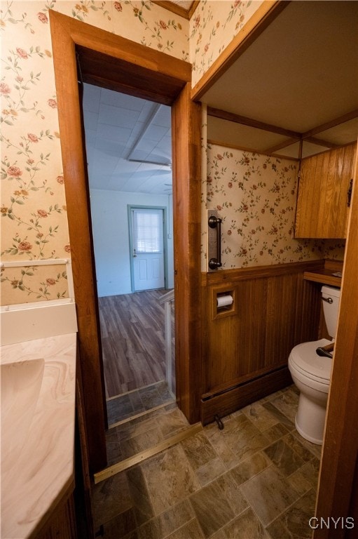 bathroom featuring toilet, wooden walls, and hardwood / wood-style floors