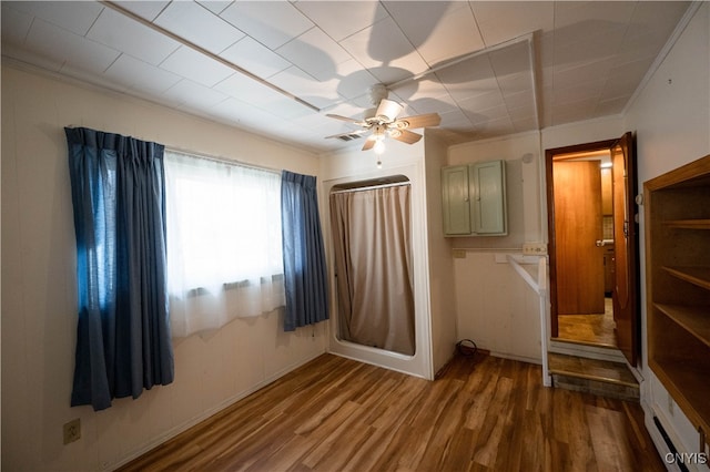 unfurnished bedroom featuring ceiling fan, crown molding, and wood-type flooring