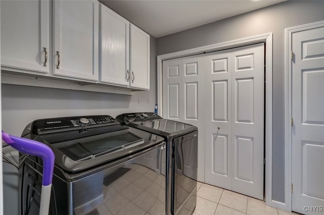 laundry area featuring washer and dryer, light tile patterned floors, and cabinets