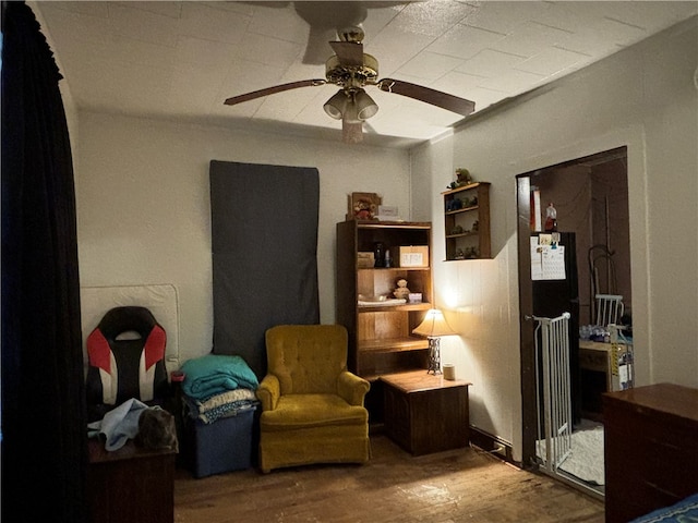 sitting room with ceiling fan, wood-type flooring, and ornamental molding