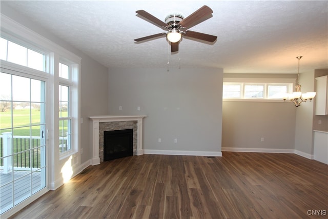 unfurnished living room with dark hardwood / wood-style floors, a tiled fireplace, a textured ceiling, and ceiling fan with notable chandelier