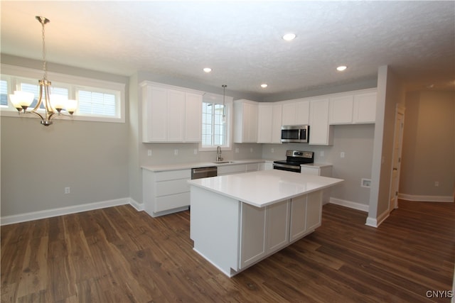 kitchen with dark wood-type flooring, stainless steel appliances, sink, a center island, and white cabinetry