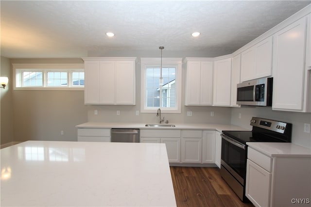 kitchen with a healthy amount of sunlight, appliances with stainless steel finishes, sink, and hanging light fixtures