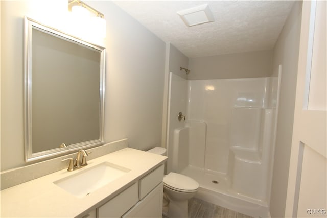 bathroom with toilet, a textured ceiling, vanity, and a shower