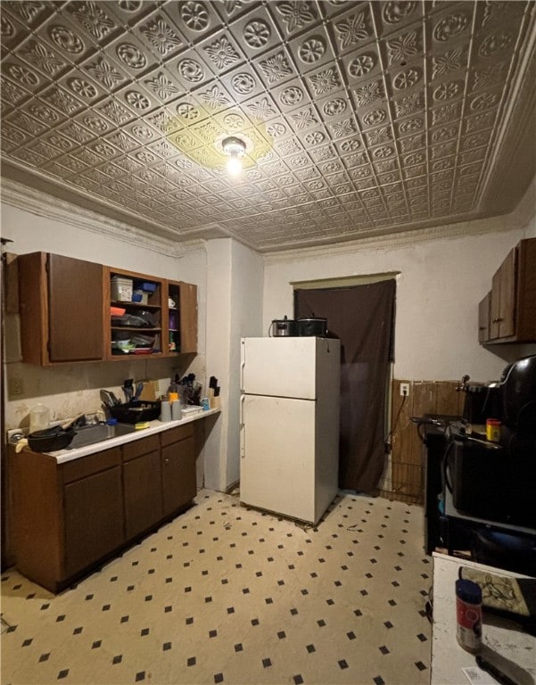 kitchen featuring dark brown cabinetry, ornamental molding, and white fridge