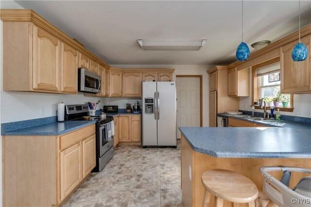 kitchen featuring light brown cabinetry, sink, decorative light fixtures, appliances with stainless steel finishes, and a kitchen breakfast bar