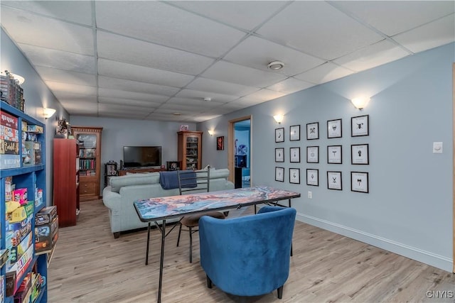 game room with a paneled ceiling and light wood-type flooring